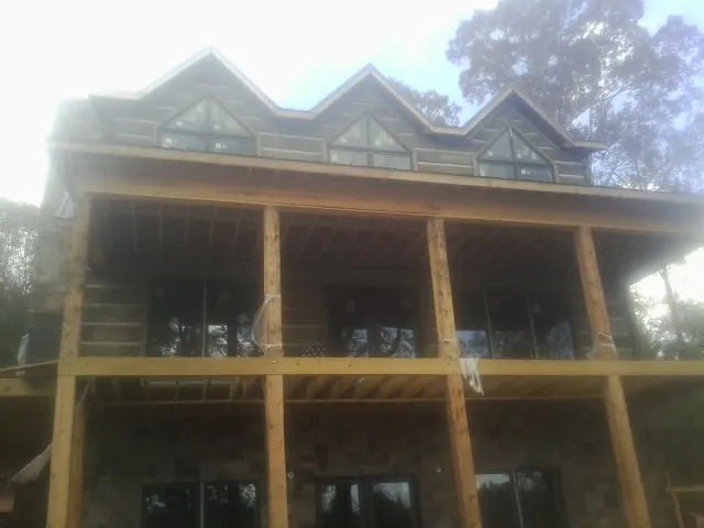 Dormers and porch framing on a large log home under construction — Roof Coating work by our crew in Turtle Lake