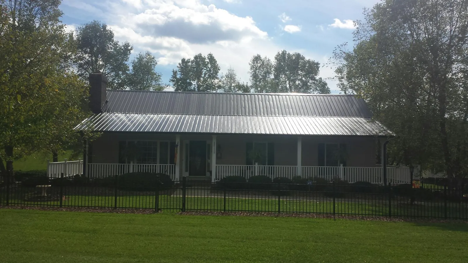 Gray metal roof on a brick ranch with a full width front porch — Gutter Guard Installation work by our crew in Turtle Lake
