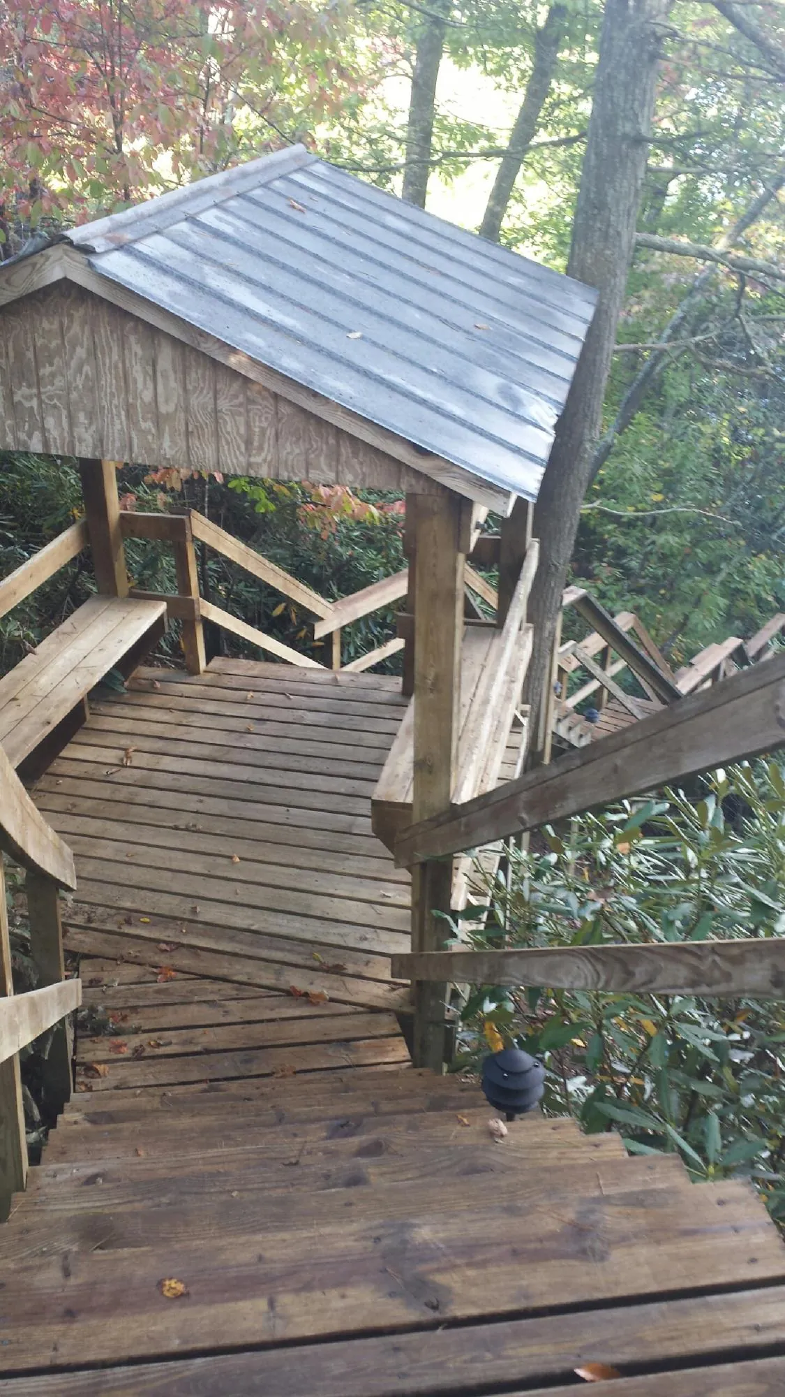 Metal roofed shelter over wooden steps on a wooded walkway — Skylight Repair & Installation work by our crew in Turtle Lake