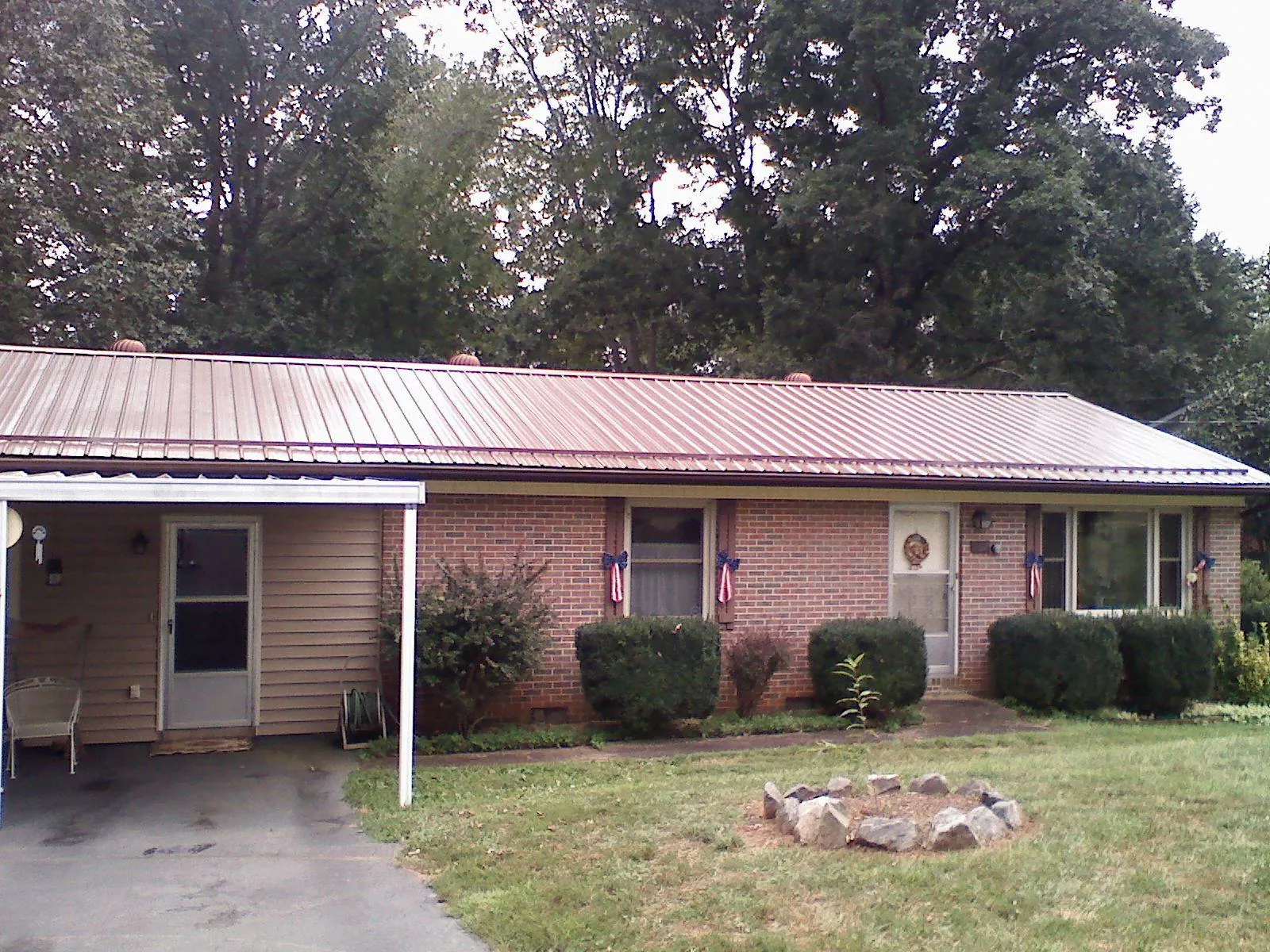 Bronze metal roof and carport on a brick ranch home — Roof Repair work by our crew in Turtle Lake