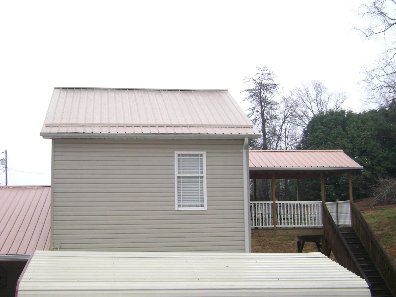 Tan metal roofs on a two story addition and attached porch, from a Roof Replacement job in Turtle Lake