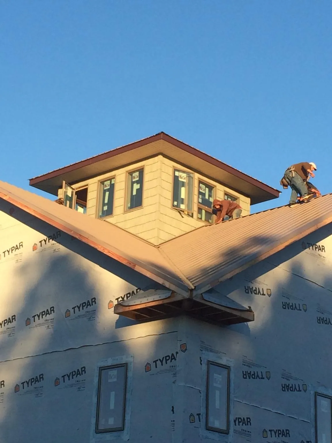 Roofers working around a rooftop cupola on a new metal roof at sunset — Roof Waterproofing in Turtle Lake by Roofing Brothers